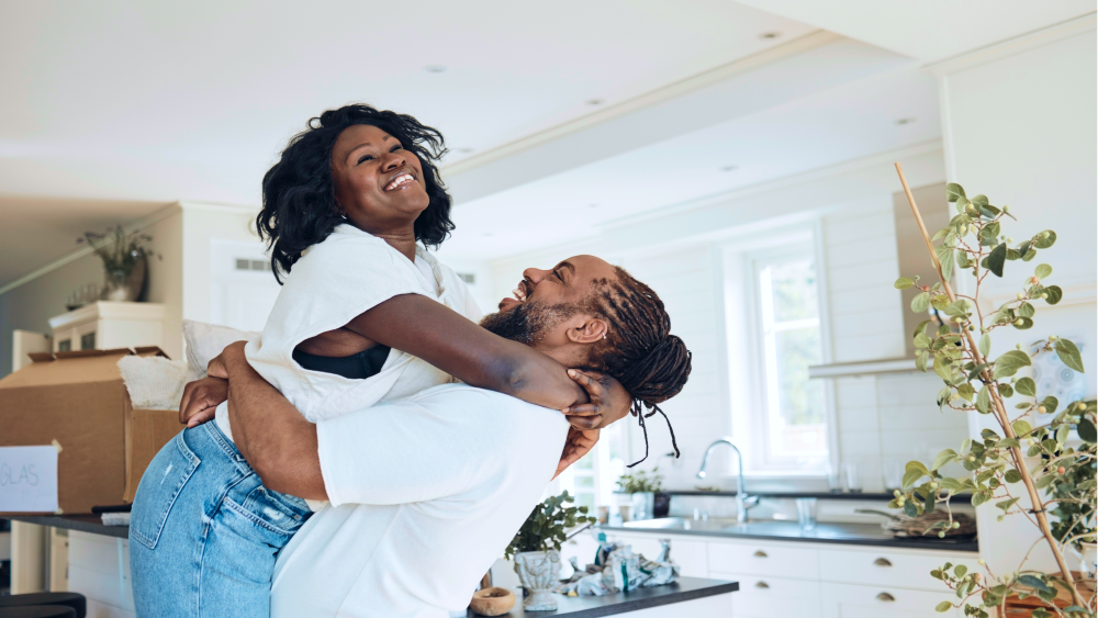 Laughing couple embracing in kitchen with moving boxes