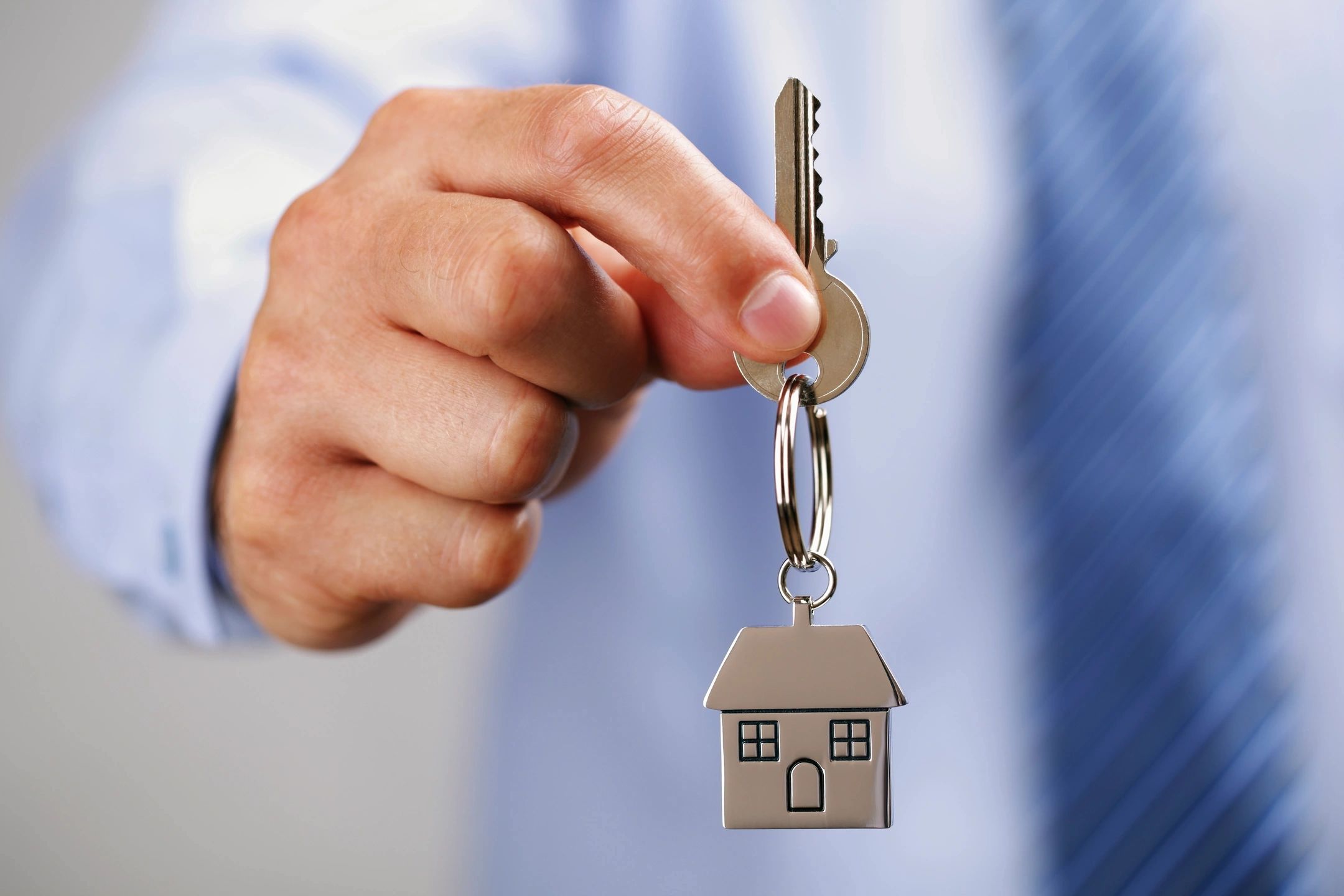 Hand holding key with house-shaped keychain