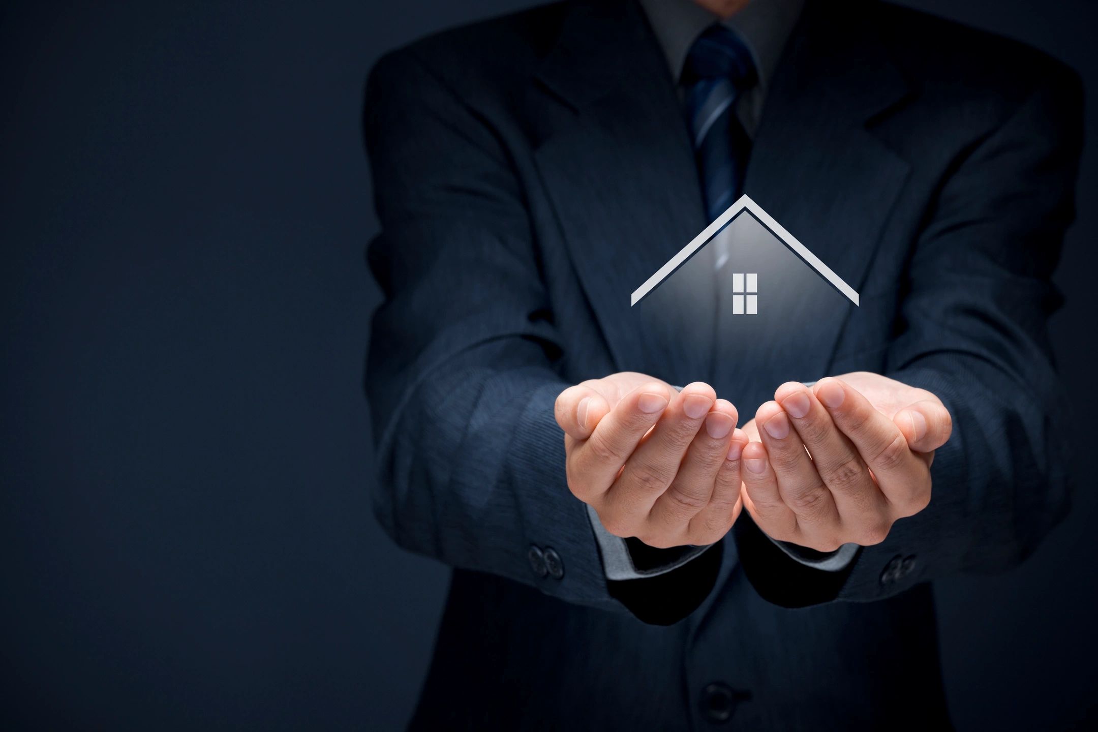Person in suit holding glowing house icon