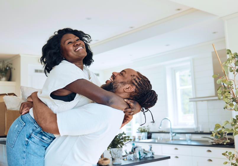 Laughing couple embracing in kitchen with moving boxes